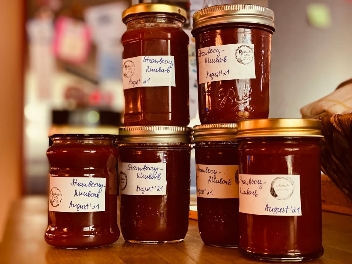 Cluster of homemade jam jars filled with fruit preserves on a wooden bench